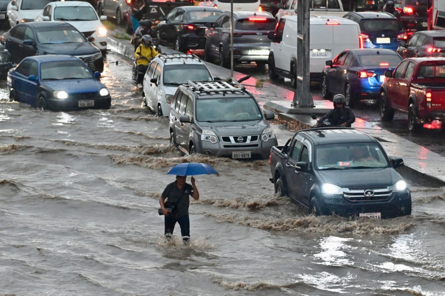 Un hombre camina por aguas anegadas tras fuertes lluvias en el norte de Guayaquil, Ecuador. AFP