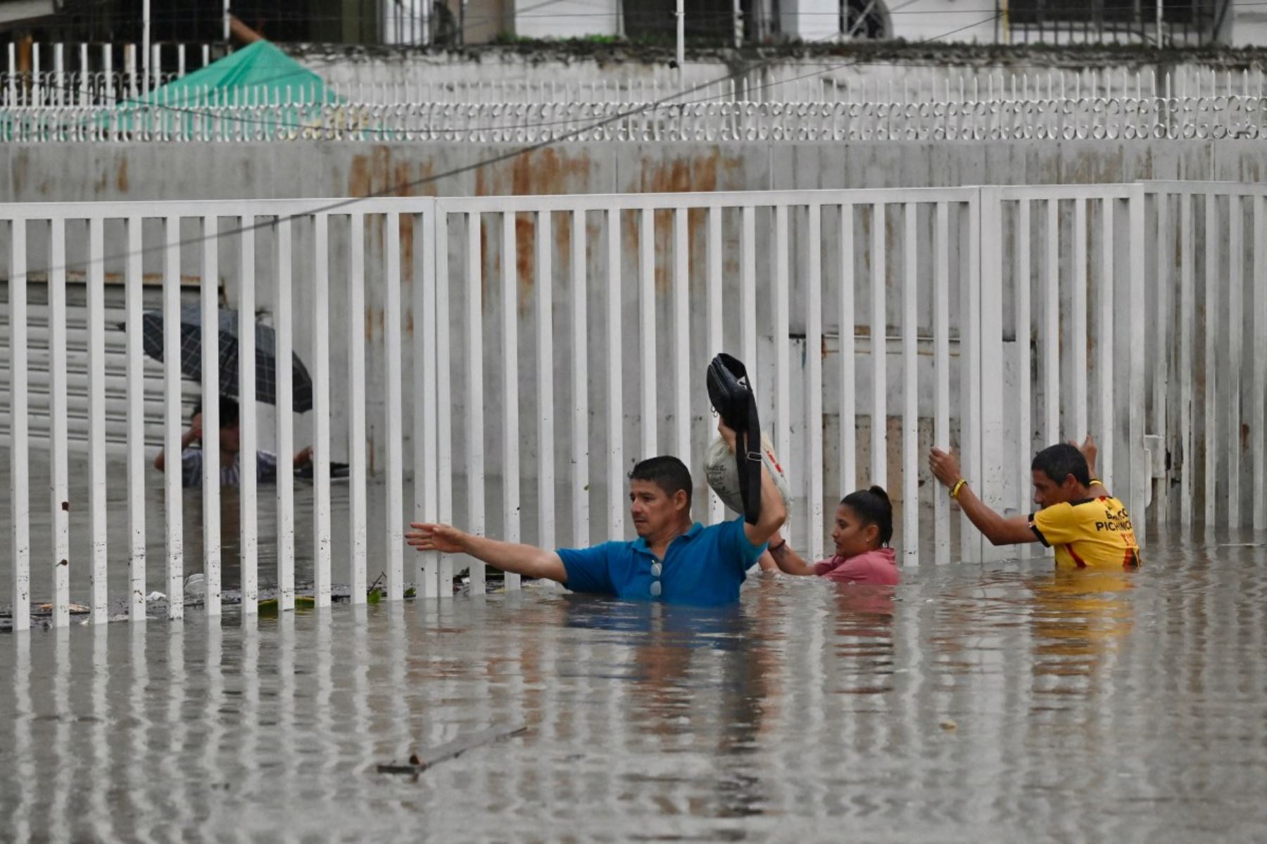 Personas caminan por aguas anegadas tras fuertes lluvias en el norte de Guayaquil, Ecuador. AFP