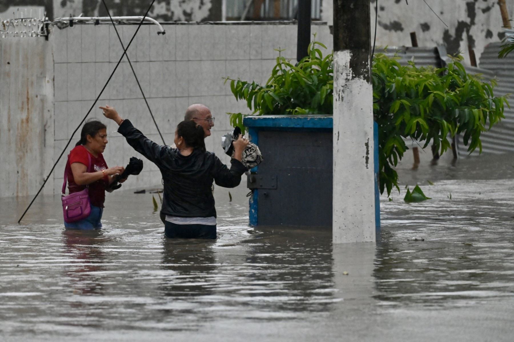 Personas caminan por aguas anegadas tras fuertes lluvias en el norte de Guayaquil, Ecuador. AFP