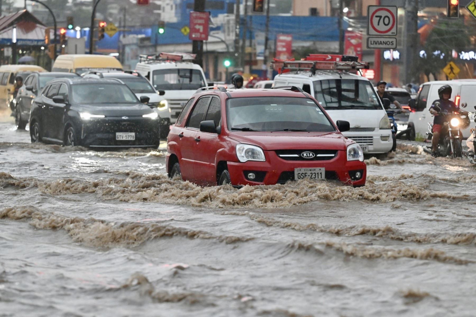 Vehículos avanzan a través de aguas anegadas tras fuertes lluvias en el norte de Guayaquil, Ecuador. AFP