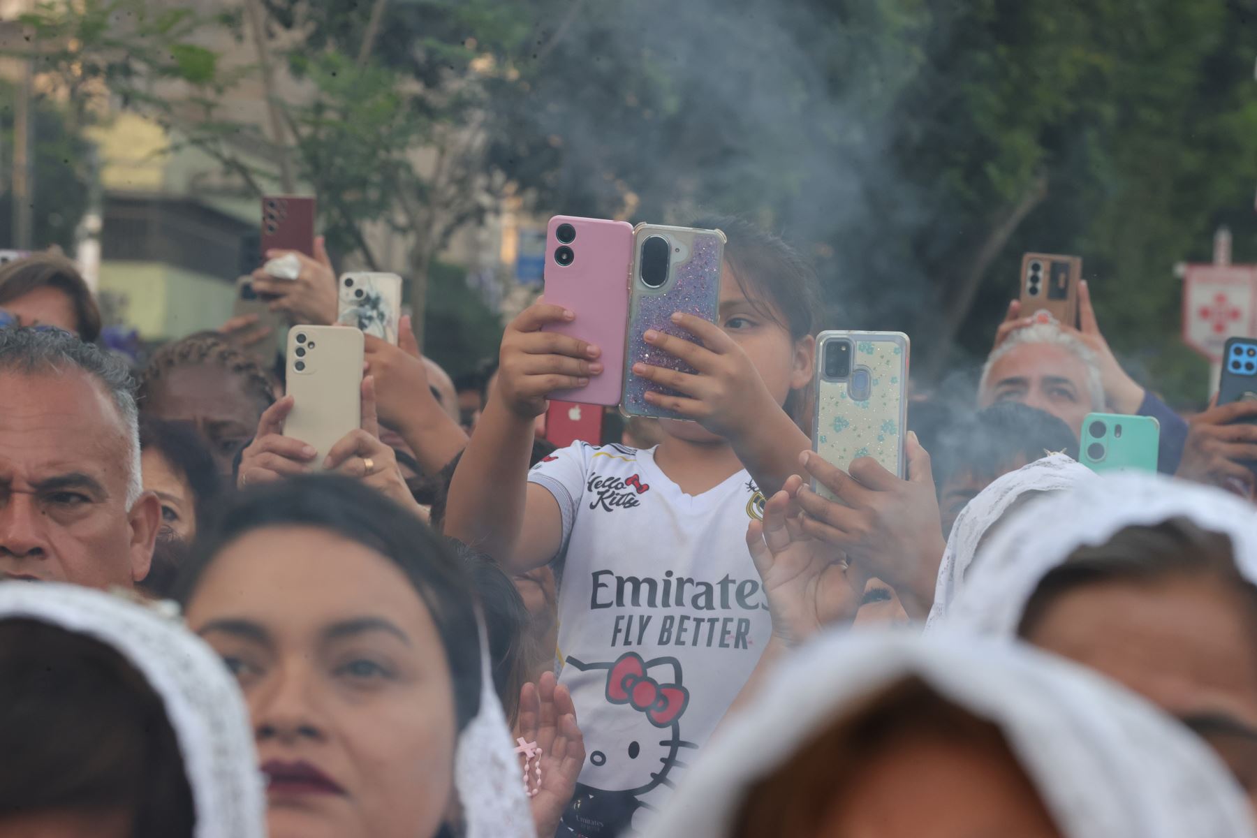 Los fieles registran con sus teléfonos celulares el paso de la procesión del Señor de los Milagros, mientras el humo del incienso se eleva entre los asistentes. La jornada religiosa congrega a numerosos devotos en las calles de la capital. Foto: ANDINA/Carlos Lezama.