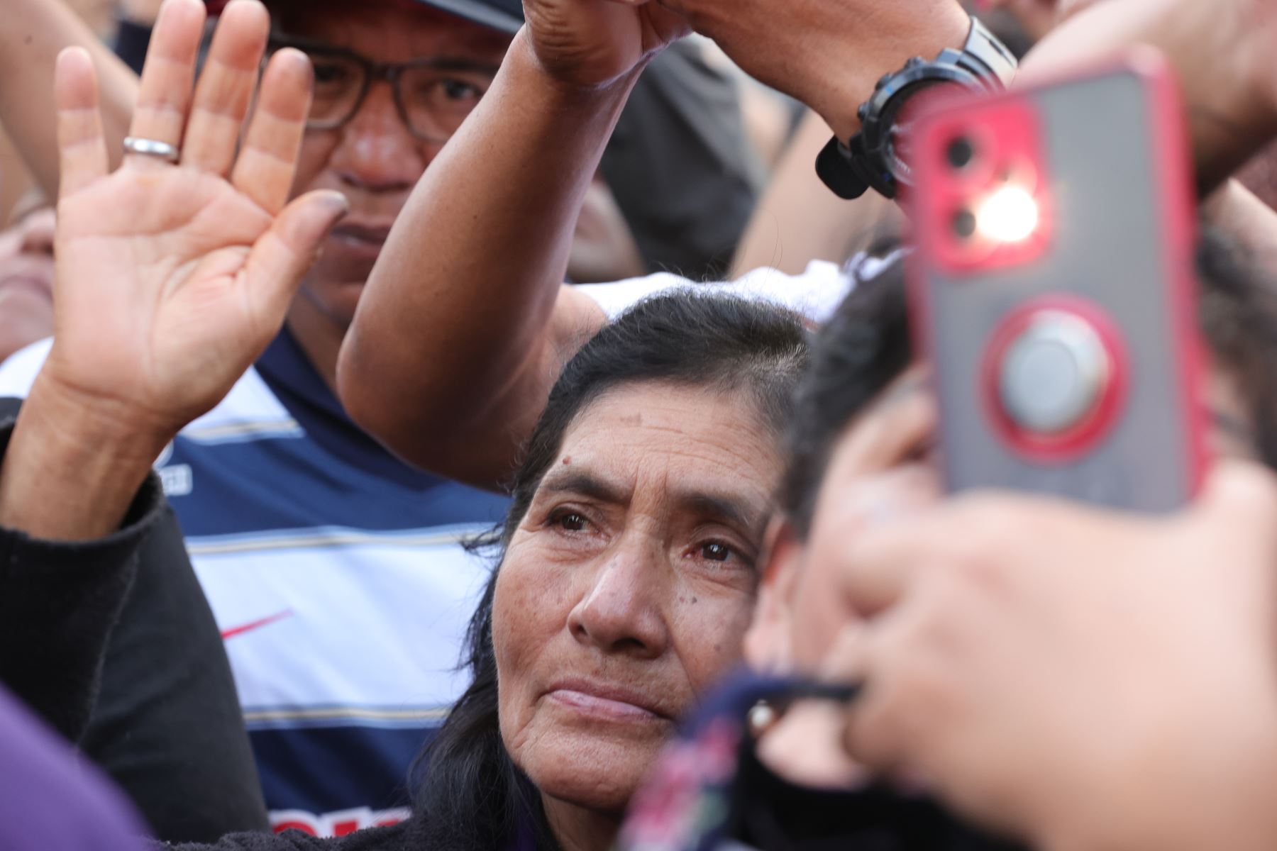 Un devoto levanta la mano entre la multitud que participa en la procesión del Señor de los Milagros, mientras otros asistentes registran la jornada con sus teléfonos celulares. La imagen realiza este miércoles 28 de octubre su cuarto recorrido por Lima. Foto: ANDINA/Carlos Lezama.